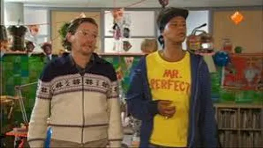 Twee mannen staan naast elkaar in een kleurrijke kamer; één draagt een crèmekleurige trui, de ander een geel T-shirt met opdruk.
